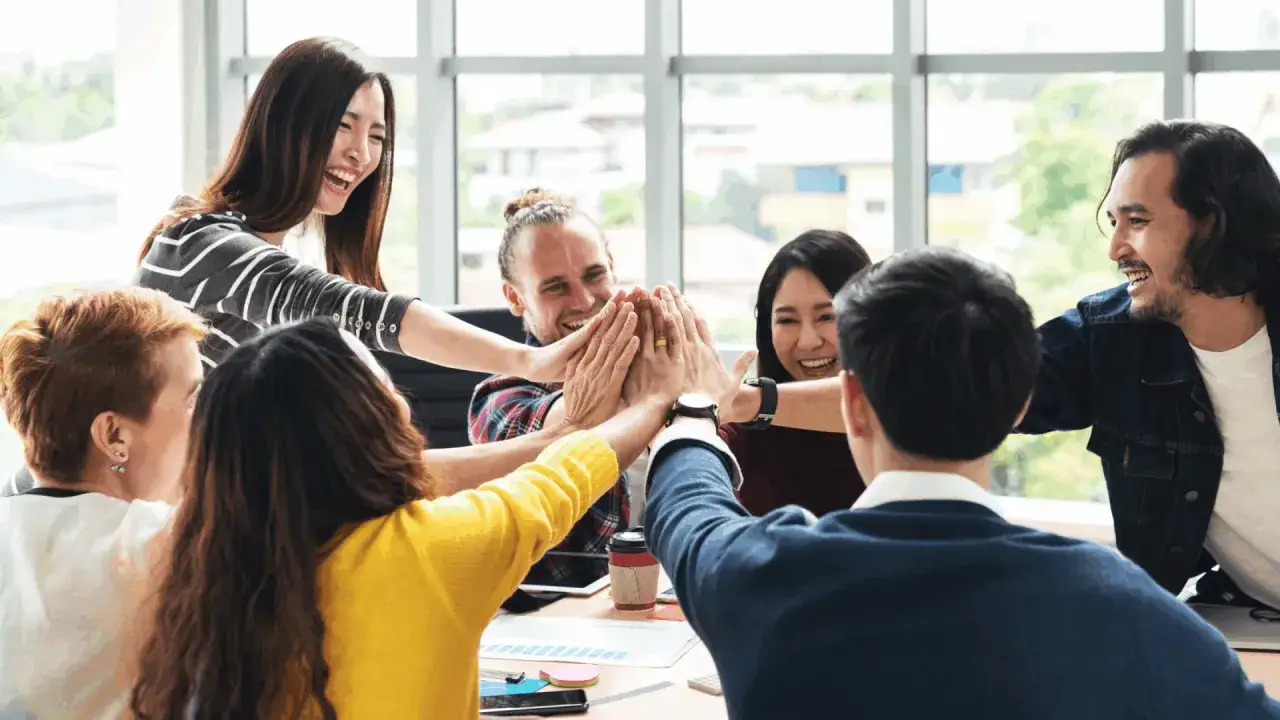 Een team geeft elkaar een high five, een teken van informeel leiderschap en teamgeest. Ze lachen en vieren succes.