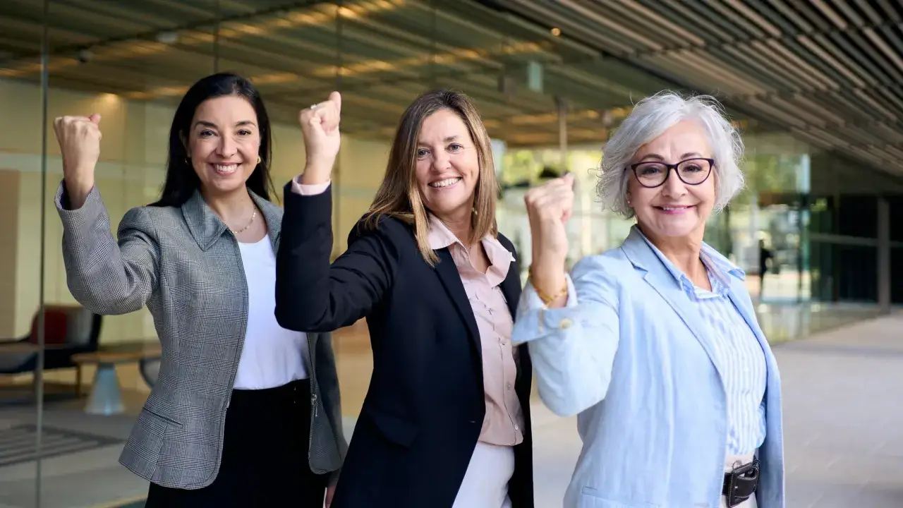 Drie zakenvrouwen, jong en oud, vieren succes. Geen leeftijdsdiscriminatie ouderen hier, alleen kracht en overwinning!