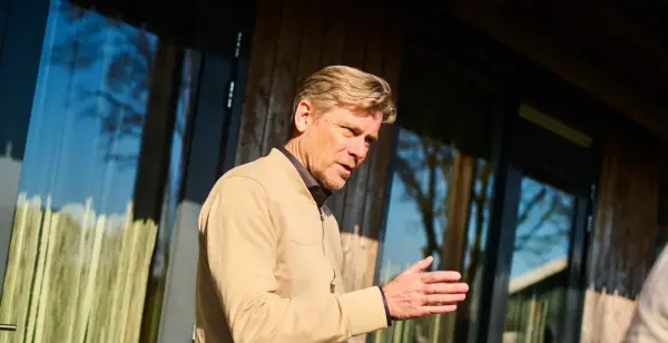 Man met blonde haren, gekleed in een beige jasje, legt met zijn hand uit hoe wordt ik assertiever.
