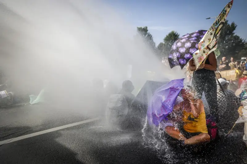 Protest met waterkanonnen, mensen met paraplu's tonen burgerlijke ongehoorzaamheid.