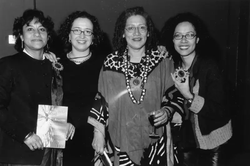 Vier vrouwen, symbool voor intersectionaliteit en feminisme, poseren met een boek en een glas wijn.